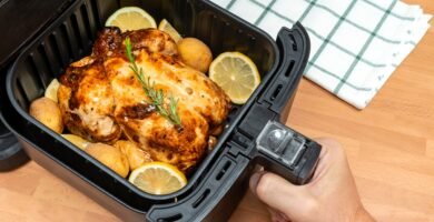 100 Recetas con Freidora de Aire: De Pollo Crujiente a Postres en Minutos 13 Cestas y platos de comidas crujientes y saludables recién sacados de una freidora de aire en una cocina moderna.