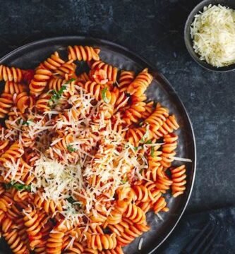 Plato de pasta fusilli con salsa de tomate y queso rallado — receta económica y casera de pasta para blog de comidas baratas.