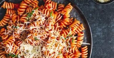 Plato de pasta fusilli con salsa de tomate y queso rallado — receta económica y casera de pasta para blog de comidas baratas.