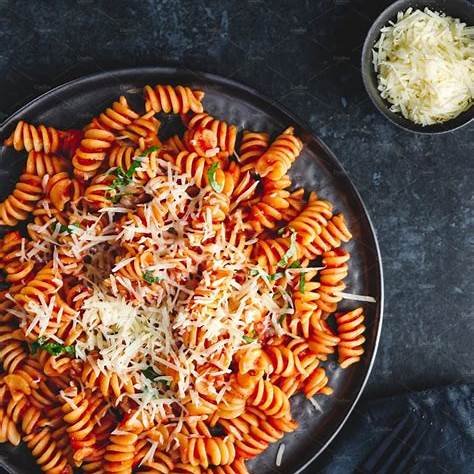 Plato de pasta fusilli con salsa de tomate y queso rallado — receta económica y casera de pasta para blog de comidas baratas.