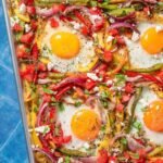 Receta casera de huevos al horno en sartén con pan, verduras y salsa: presentación tipo brunch gourmet económico.