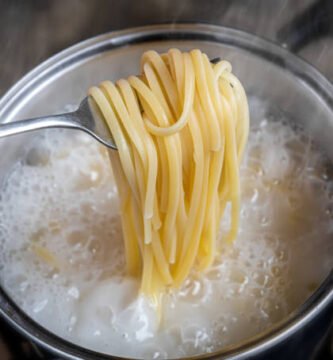 spaghetti cociéndose en agua hirviendo dentro de una olla de acero inoxidable