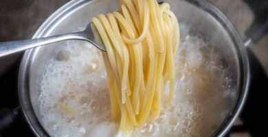 spaghetti cociéndose en agua hirviendo dentro de una olla de acero inoxidable